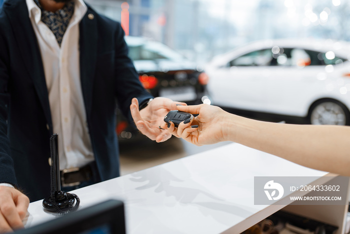 Man takes the key from new auto in car dealership