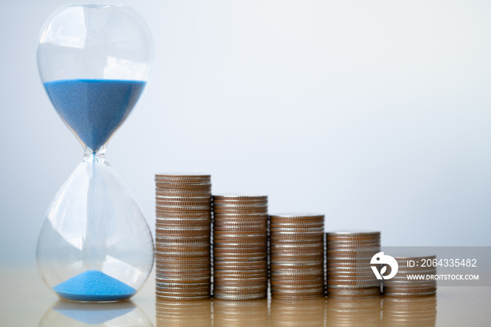 Hourglass blue sand and stack of coins. Business investment growth concept. money saving and Investm