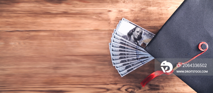 Graduation hat and money on wooden table.