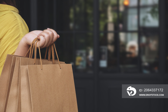 Hand of woman holding paper bags enjoy with shopping in the mall.