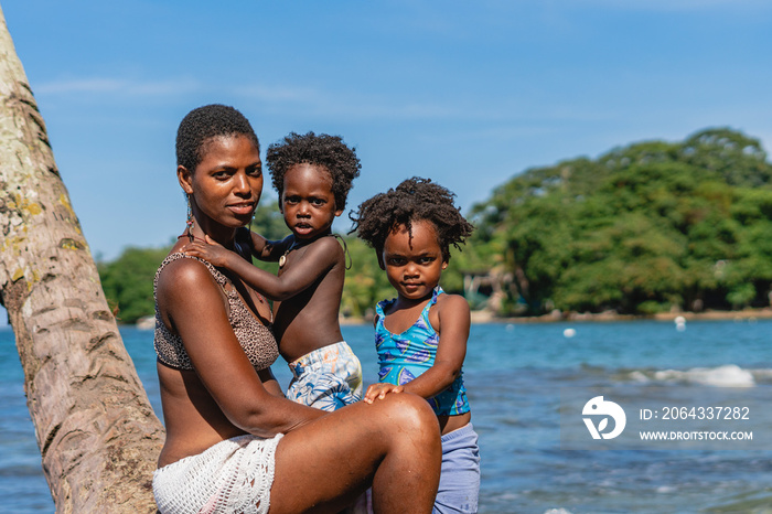 Imagen de una hermosa familia afro americana sobre una palmera viendo a cámara disfrutando de un día