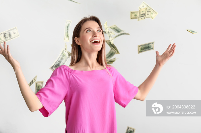 Happy young woman and falling dollar banknotes on white background