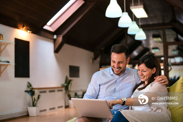 Happy couple with laptop spending time together at home