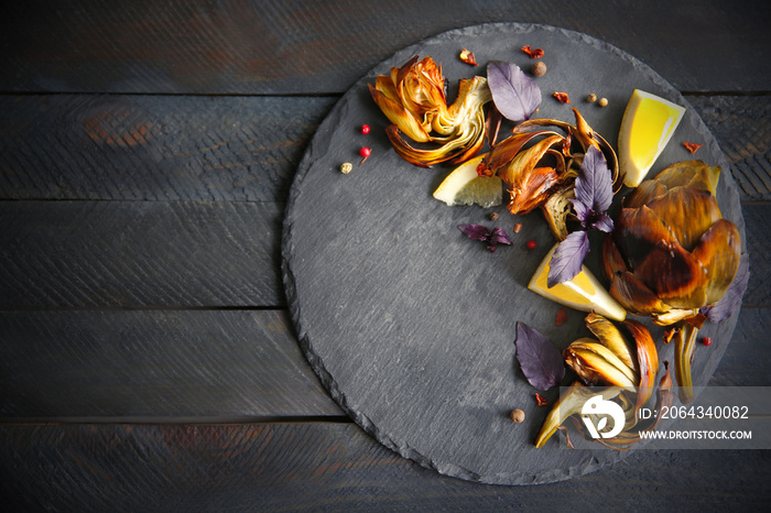 Baked artichokes with spices on wooden background