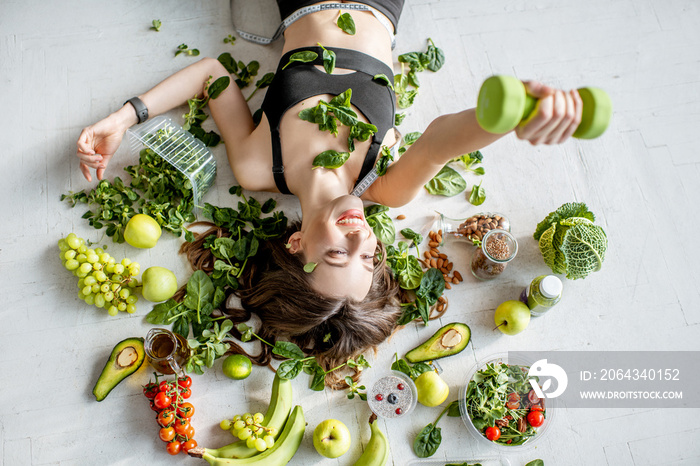 Beauty portrait of a sports woman surrounded by various healthy food lying on the floor. Healthy eat