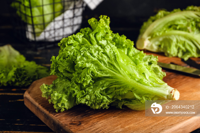 Board with fresh lettuce on dark wooden table, closeup