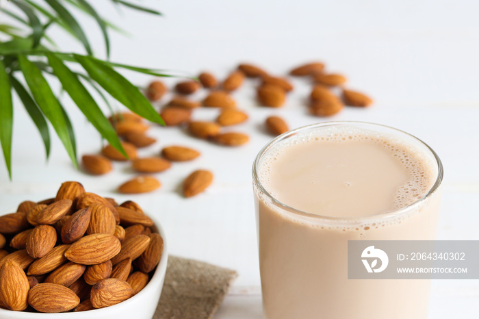 Almond organic milk in drinking glass close-up on the table with almonds. Vegan plant-based product.