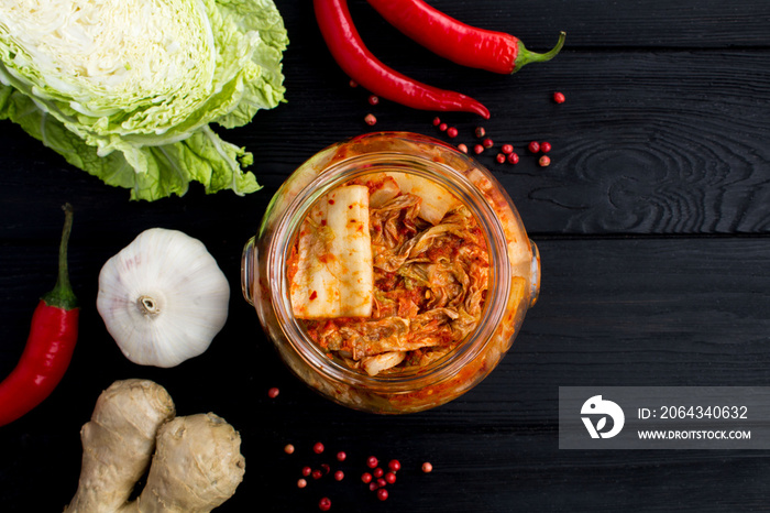 Kimchi in the glass jar and ingredients on the black wooden  background.Top view.Copy space.