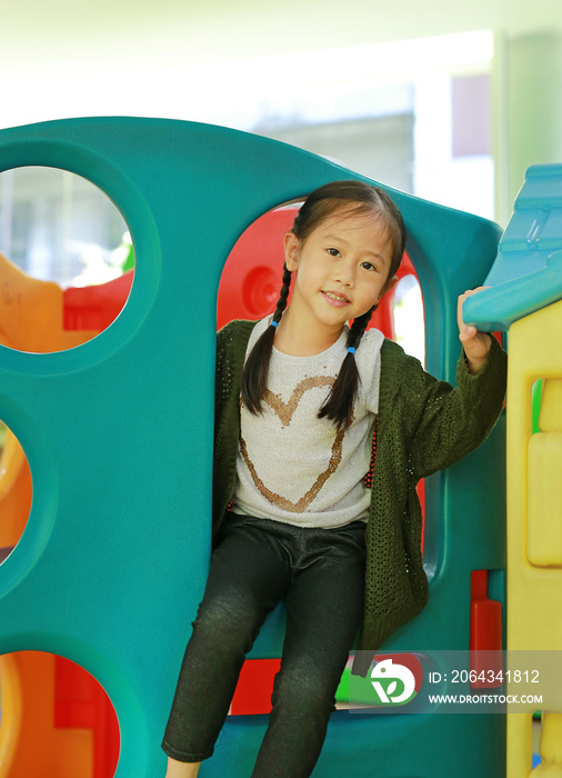 Adorable little Asian child girl playing toy playhouse at indoor playground.