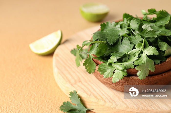 Bowls with fresh cilantro and lime on color background, closeup