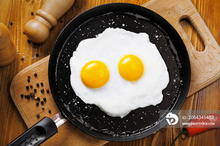 Fried eggs for delicious healthy easy breakfast on a table. Fresh homemade meal on a frying pan. Tra