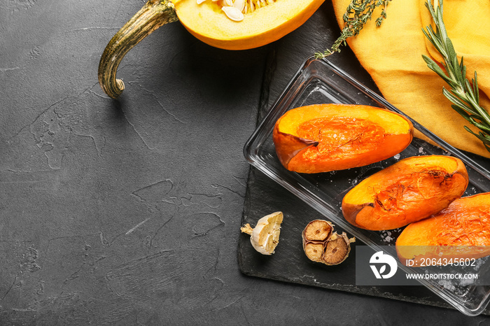 Dish with baked pumpkin pieces on black background