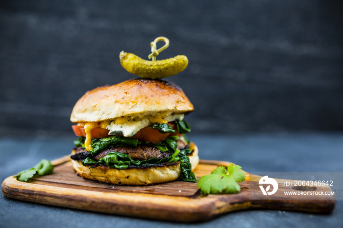 Tasty grilled vegetarian Champignon burger with spinach lettuce and blue cheese served on wooden tab