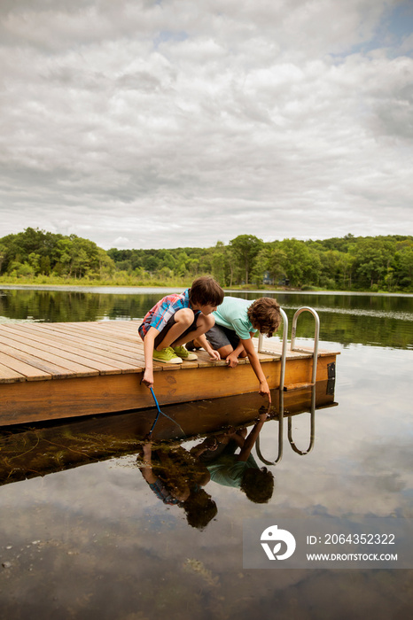 Boys playing on jetty by lake