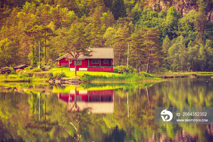 wooden cabin in forest on lake shore, Norway