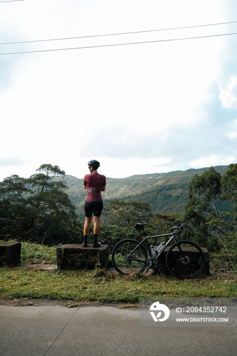 A young female cyclist looking at a view in the mountains during her bike ride.