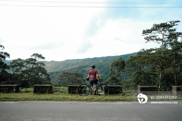 A young female cyclist looking at a view in the mountains during her bike ride.