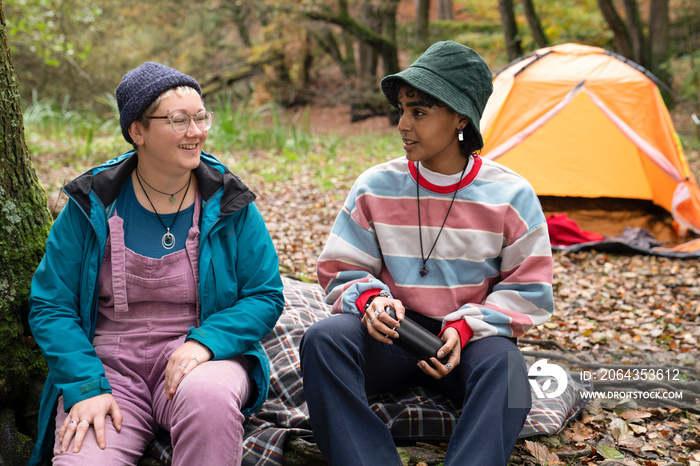 Smiling female friends camping in forest