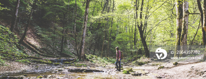 Hiker woman with backpack walking on path in summer forest