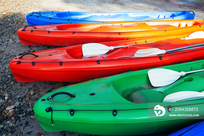 海滩上五颜六色的独木舟的近景，准备使用。阳光明媚
