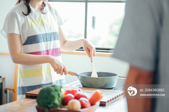 料理をする女性と見ている男性（顔なし）