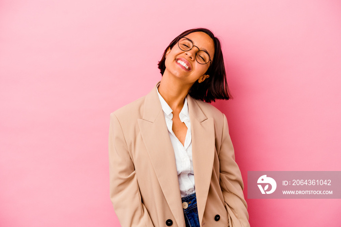 Young business mixed race woman isolated on pink background relaxed and happy laughing, neck stretch