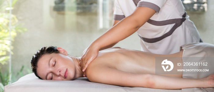 Back, neck and shoulder massage in the spa salon. Young woman receiving a luxurious oil massage trea