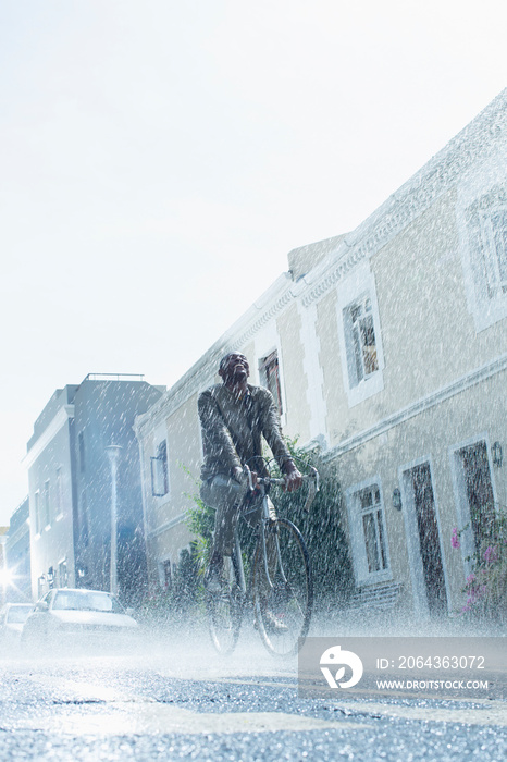 在下雨的街道上骑自行车的无忧无虑的人