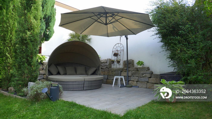 Gartenterrasse mit Loungegruppe und Sonnenschirm in einer Gartenecke mit Säulen-Faulbaum und umgeben