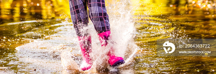 穿着粉色橡胶靴的孩子在雨中跳过水坑