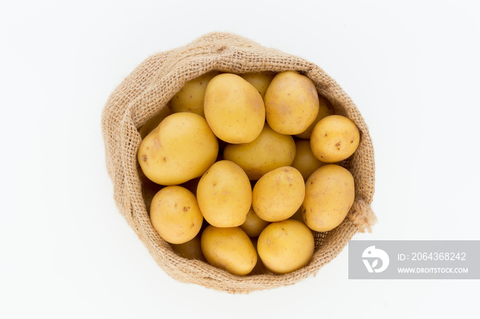 Sack of fresh raw potatoes on wooden background, top view