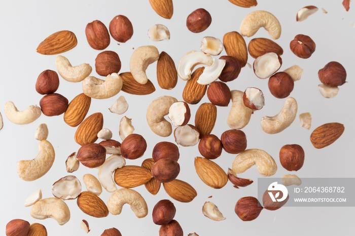 Flying nuts on a grey background: almonds, cashew and hazelnat