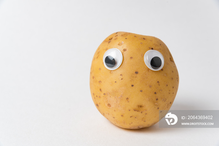 Sad raw potatoes with Googly eyes on white background. Food with funny face