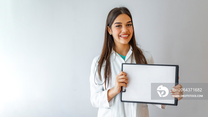 Happy doctor holding empty blank in hands. Female doctor showing a clipboard with blank paper. Close