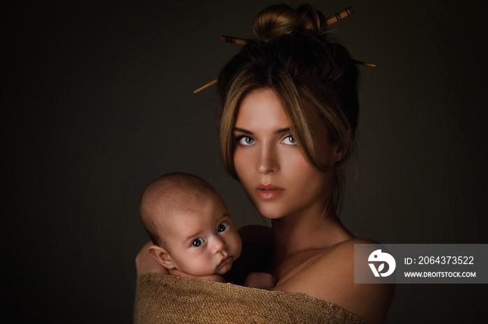 美丽的母亲和她的小宝宝裹着麻衣