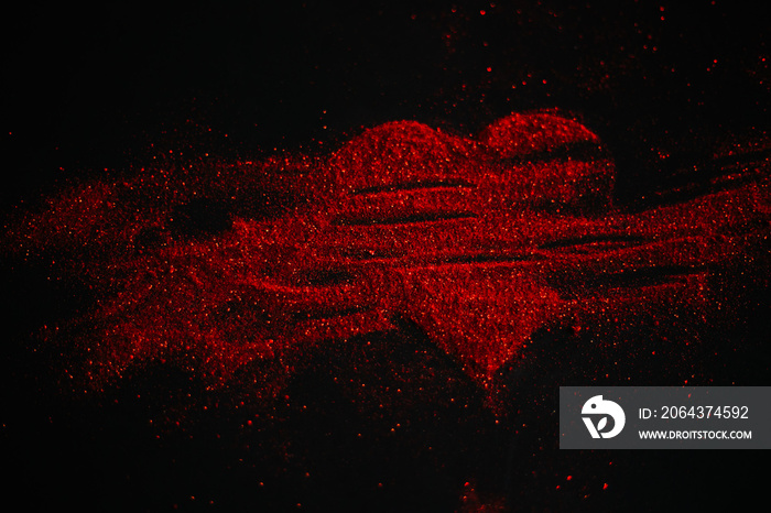 黑色背景上由闪闪发光的红色心形图案。闪闪发光的灰尘符号。