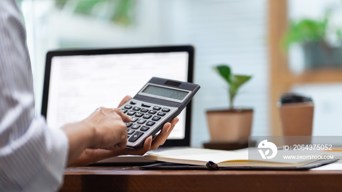 Concept of accounting work, business man doing paperwork using a calculator at the office and Financ