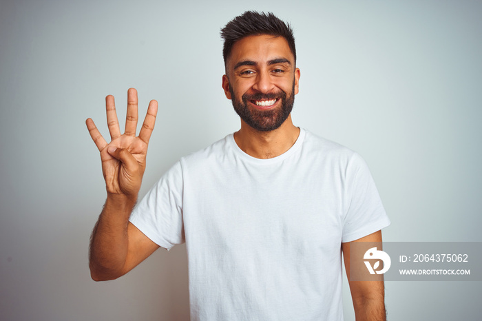 Young indian man wearing t-shirt standing over isolated white background showing and pointing up wit