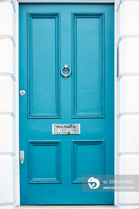 Beautiful blue door with letterbox in a white house facade in Notting Hill