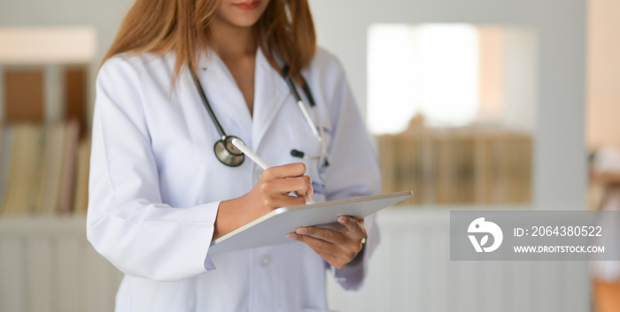 Cropped shot of young doctor checking patient chart while using digital tablet