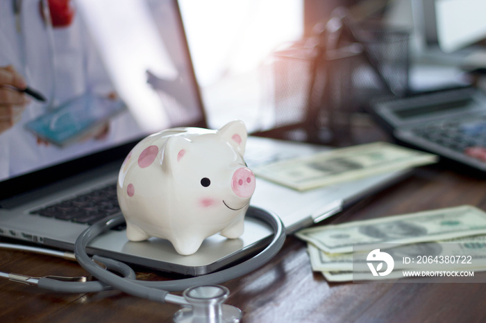 Piggy bank and stethoscope on computer laptop, money savings, medical insurance and health care fina