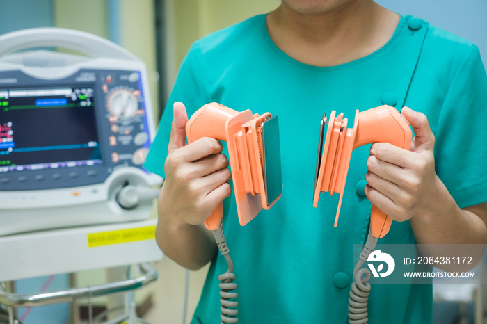 Nurse holding defibrillator, performing defibrillation on a patient, saving a human life.