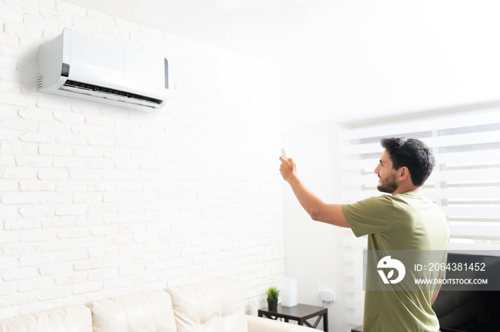 Man Turning On Air Conditioner With Remote