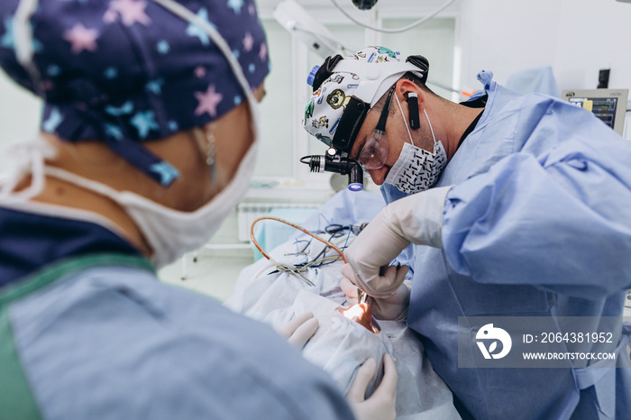 外科医生和他的助手在医院手术室做整容手术。我们戴着口罩的外科医生