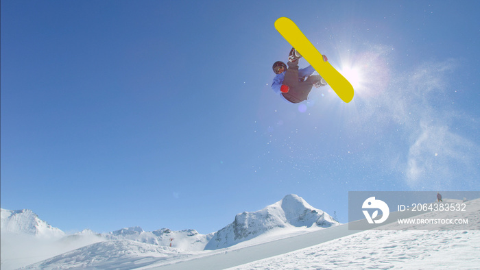 年轻的职业单板滑雪运动员在半管道雪上公园跳过太阳