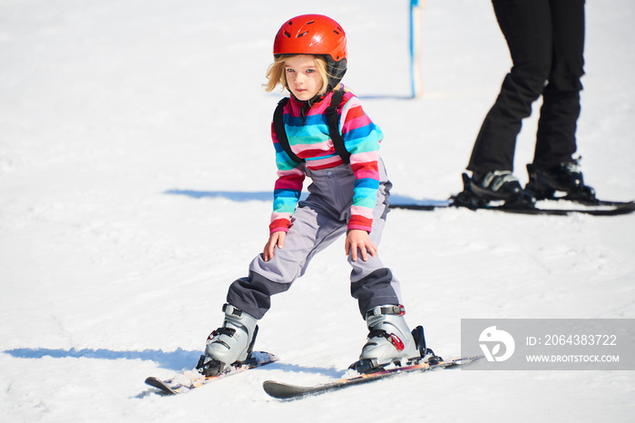 小女孩在山上滑雪。带着安全帽和护目镜的活泼孩子。为幼儿举办滑雪比赛