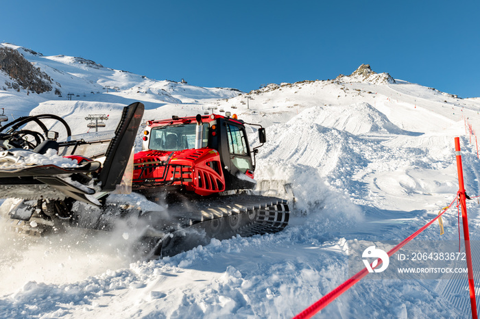 Red modern snowcat ratrack with snowplow snow grooming machine preparing ski slope piste hill at alp