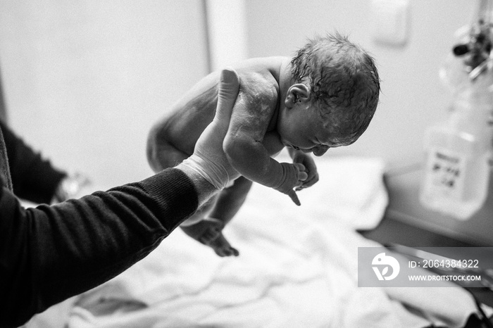 Newborn child seconds and minutes after birth. Doctor hands with new born baby. Medical check up of 