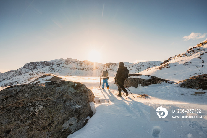 Two mountaineer hiking to peak mountain on snow field at sunset