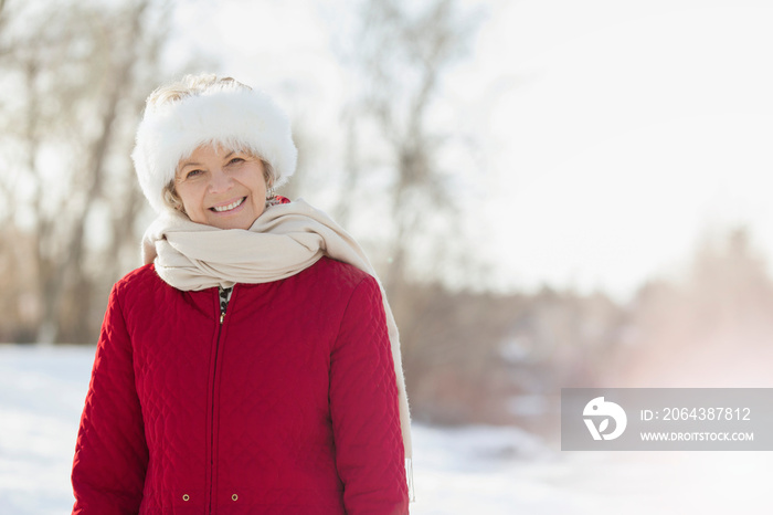 Portrait of happy senior woman standing in snow